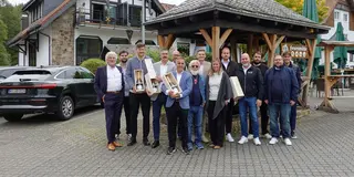 TUBELESS-Gesellschafter stehen vor einem Fachwerkhaus, ein paar halten Champagnerflaschen in den Händen